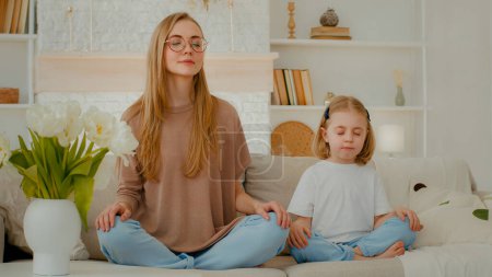 Photo for Caucasian woman mom with little child girl sitting home at couch in lotus position closed eyes meditate together. Family meditating mother teach meditation small daughter adorable baby kid breath - Royalty Free Image