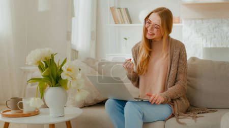 Téléchargez les photos : Caucasian woman in glasses happy girl lady student businesswoman freelancer female with laptop sitting on couch celebrating good news exams admission business great results win success victory winning - en image libre de droit