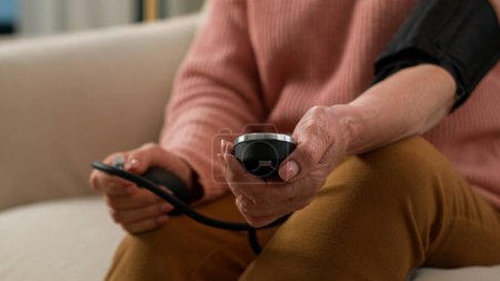 Téléchargez les photos : Malade caucasien grand-mère utiliser la mesure numérique de la pression artérielle malaise femme âgée vérifier l'hypotension avec manomètre à la maison malsaine vieille femme retraitée examen battement de coeur avec tonomètre - en image libre de droit