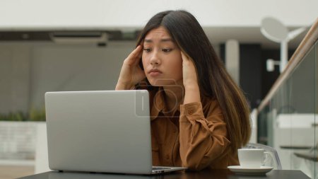 Téléchargez les photos : Épuisé surmené asiatique chinois japonais femme étudiante fille étudier en ligne avec ordinateur portable dans café fatigué malade femme d'affaires penser difficile décision pensée souffrir maux de tête massage temples douleur tête - en image libre de droit