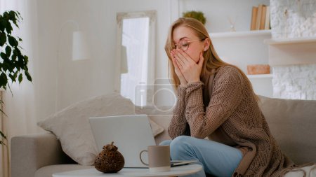 Photo for Caucasian shocked woman in glasses looking at laptop reading bad news close mouth with hands holding head with shock failure student girl lost with computer businesswoman worry about business problem - Royalty Free Image