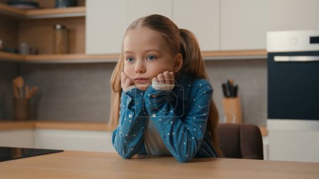Photo for Moving camera sad little offended Caucasian child girl at kitchen boring stressed need parents help custody adoption family misunderstanding upset bored daughter unhappy lonely kid stress at home - Royalty Free Image