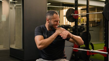 Téléchargez les photos : African American man guy in gym doing sport exercise with dumb-bells workout sportsman athlete lifting up heavy dumbbells weights feel sharp pain in shoulder hand painful injury trauma ache stretching - en image libre de droit