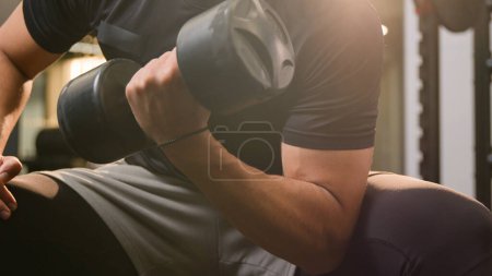 Foto de Close up moving shot strong athletic African American ethnic man guy in gym doing sport exercise with dumb-bell curl biceps workout male sportsman athlete hands arms lifting up heavy dumbbell weights - Imagen libre de derechos