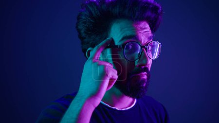 Photo for Indian man developer coding worker computer smart clever hacker in glasses neon ultraviolet studio background thinking hard brain power mental strength think about it ponder problem solving IQ gesture - Royalty Free Image