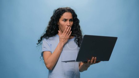Téléchargez les photos : Stressé Arabe femme hispanique fille choqué étonné insatisfait Arabe femme bouleversée par l'échec de l'ordinateur portable difficultés d'affaires femme d'affaires problème de projet erreur informatique fond bleu - en image libre de droit