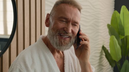 Photo for Caucasian retired elderly man senior mature old 60s male pensioner talking mobile phone talk smartphone friendly conversation speaking in bathroom answer call morning hygiene in bath communication - Royalty Free Image