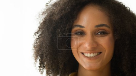 Foto de Primer plano retrato femenino mujer afroamericana feliz étnica hermosa joven mujer de negocios con pelo rizado maquillaje natural belleza cuidado de la piel sonriente chica toothy dental cándida sonrisa en estudio blanco - Imagen libre de derechos