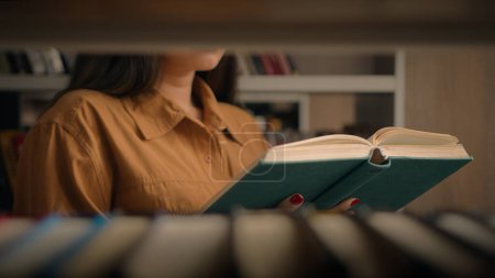 Photo for Unrecognizable woman reading book in university library near bookcase smart female girl college student teacher read textbook literature prepare for exam studying homework view through bookshelf books - Royalty Free Image