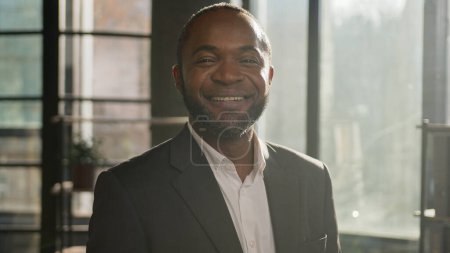 Téléchargez les photos : Portrait professionnel homme d'âge moyen afro-américain souriant entrepreneur chef d'entreprise banquier employeur mature homme d'affaires ethnique heureux dans les rayons de soleil soleil bureau de soleil regardant caméra dents sourire - en image libre de droit