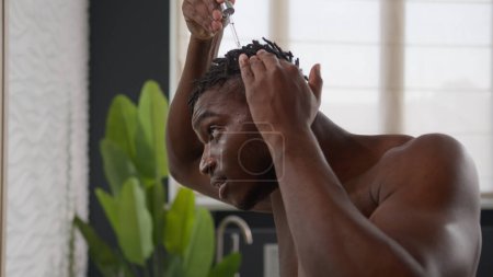 Photo for African American man applying argan oil serum on hair roots dreadlocks healthy massage morning bathroom routine male guy drip keratin cosmetic liquid treatment baldness alopecia beauty care for hairdo - Royalty Free Image