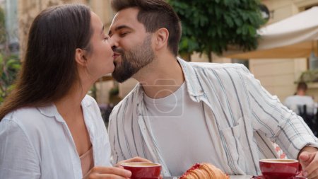 Téléchargez les photos : Couple caucasien européen amoureux manger le petit déjeuner dans la ville café petit ami embrasser petite amie sourire rire plaisir harmonie relation plaisir affectueux aimer homme et femme sur romantique date en plein air - en image libre de droit