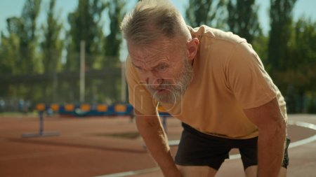 Photo for Caucasian exhausted elderly man runner tired jogging sport activity healthy lifestyle stadium outside running exercise fitness training outdoors old senior male have break rest hard breathing dyspnea - Royalty Free Image