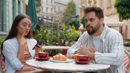 Photo for European young couple in city cafe woman smiling laughter emotional texting smartphone ignore man fixed gaze distant frustrated relationship problem indifference outdoors breakfast internet addiction - Royalty Free Image