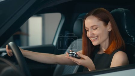 Foto de Cliente sonriente feliz Mujer de negocios caucásica sentada dentro de un coche nuevo sonrisa cliente comprador mujer conductor propietario chica en vehículo de lujo en la tienda de automóviles salón auto alquiler transporte compra mostrando la clave - Imagen libre de derechos