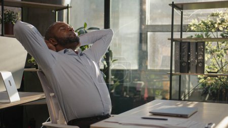 Photo for Relaxed African American mature businessman senior happy man finish computer work close laptop relaxing in sunny warm comfortable office male specialist stretch muscles put hands behind head day end - Royalty Free Image