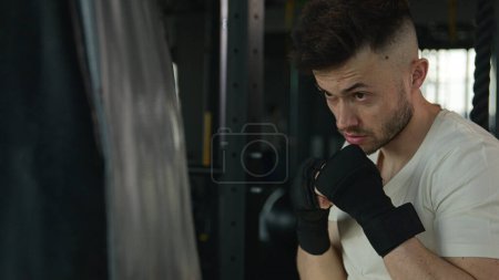 Photo for Active motivated sportsman male professional fighter boxer training boxing with punching bag in gym tired man Caucasian guy wipe sweat box workout in sport club training power hit punch beating fight - Royalty Free Image