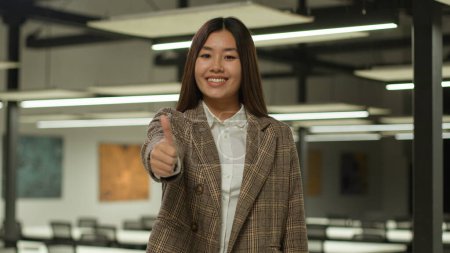 Téléchargez les photos : Sourire asiatique fille étudiant coréen heureux femme d'affaires japonais femme d'affaires montrant pouce vers le haut approuver geste recommander bonne idée accord soutenir excellent résultat atteindre doigt levé dans le bureau - en image libre de droit
