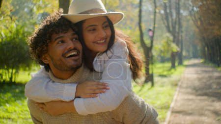Photo for Happy smiling loving multiethnic married couple african american man hispanic woman walking in park outdoors romantic date in nature guy move holding piggyback beloved girl enjoying walk closeness - Royalty Free Image