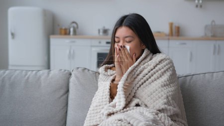 Photo for Sick Asian woman covered in blanket sneezing in paper napkin sneeze runny nose feel frozen cold unhealthy korean girl patient has covid symptom grippe nasal infectious disease health treatment at home - Royalty Free Image