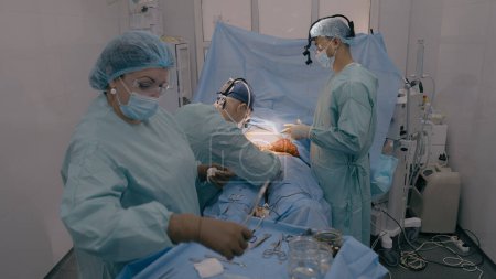 Photo for Surgery team professional doctors surgeons perform surgical operation stomach laparoscopy medical equipment nurse assistant give sterile instruments patient health treatment in operating room hospital - Royalty Free Image