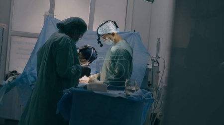 Téléchargez les photos : Processus de traumatisme chirurgie équipe professionnelle infirmières médicales médecins chirurgiens effectuer une chirurgie cardiaque neurochirurgie dans la salle d'opération stérile avec équipement hôpital moderne sauvetage d'urgence vie - en image libre de droit