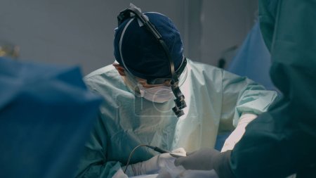 Téléchargez les photos : Chirurgiens d'équipe effectuer une opération dans la salle d'opération médecin professionnel praticien utilisant des instruments endoscopiques médicaux modernes chirurgie cardiaque enlever cancer tumeur procédure de santé chirurgicale à l'hôpital - en image libre de droit