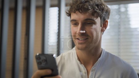 Caucasian smiling happy businessman walking in office looking at smartphone reading good news message business man smile go in company indoors hold mobile phone professional online communication chat