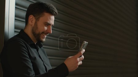 Photo for Smiling Caucasian man businessman in business center mall use mobile app chatting messages online with smartphone satisfied happy guy male client entrepreneur surfing phone internet in office booking - Royalty Free Image