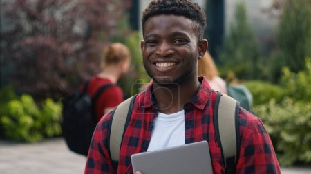 Téléchargez les photos : Heureux Afro-Américain étudiant gars homme écolier mâle en ville à l'extérieur université collège campus souriant à la caméra sourire profiter de l'éducation étude connaissance génération Z étudiants parler sur fond - en image libre de droit