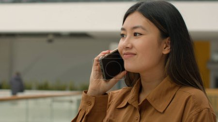 Téléchargez les photos : Asiatique femme d'affaires souriant chinois japonais fille entreprise femme employeur entrepreneur heureux coréen femme d'affaires parler téléphone mobile réponse appel parler smartphone à l'intérieur convivial bavarder au bureau - en image libre de droit