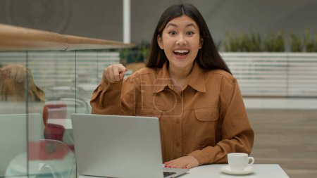 Glücklich überrascht asiatische chinesische Geschäftsfrau im Café Gewinnerin Frau gewinnt Preis auf Laptop Online-Wette feiern geschäftlichen Erfolg Sieg Schreien Zeigefinger auf Computer-Website-Werbung
