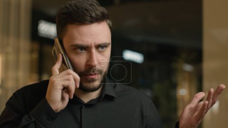 Photo for Annoyed businessman Caucasian man talk mobile phone in shopping mall solve conflict problem business anxious stressed guy calling cellphone business call quarrel talking negative emotion swear dispute - Royalty Free Image
