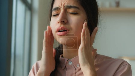 Photo for Tired sick woman arabian indian girl near window at home suffer from headache touch painful head migraine pain unhealthy ill female think difficult thoughts grief health disorder stress fatigue covid - Royalty Free Image