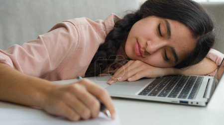 Photo for Close up tired arabian girl overworked sleepy student businesswoman falling asleep at home with laptop and notes exhausted weary woman napping close eyes sleeping on table need sleep rest lack energy - Royalty Free Image