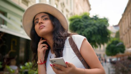 Confused Indian Arabian woman travel alone lost female tourist traveler girl on street sightseeing use mobile phone gps app looking around city trying find street explore town with smartphone outside
