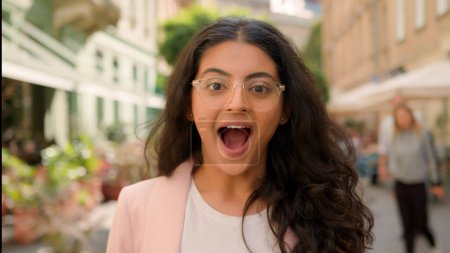 Téléchargez les photos : Jeune surprise femme excitée femme indienne arabe fille à l'extérieur. femme d'affaires positive choc souriant bouche ouverte ville rue gagner geste sincère heureux ravissement émotion étonnement annonce - en image libre de droit