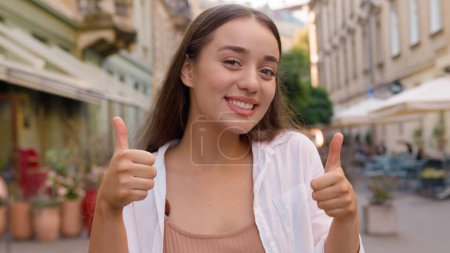 Photo for Happy caucasian woman smiling show thumb up. Enjoy happiness successful positive lady city street outside gesturing agreement young model agree winner carefree satisfied cheerful girl approval liking - Royalty Free Image