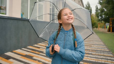 Photo for Little girl schoolgirl looking at sky frowning bad weather rain thunderstorm opening umbrella walking going street city outside smiling equipment protection rainfall drop child stroll fresh air enjoy - Royalty Free Image