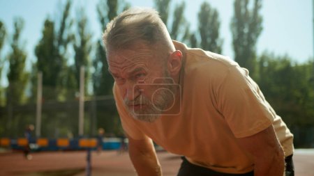 Photo for Pensioner breathing heavily after training physical activity elderly man dyspnea sporty athlete sportsman recreation stadium city outside vitality health hard working intense cardiovascular exhausted - Royalty Free Image