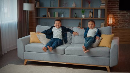 Photo for Happy family two African American ethnic little boys children siblings kids running in living room carefree funny play jumping on soft sofa laugh jump on cozy couch relocation at home playing game - Royalty Free Image