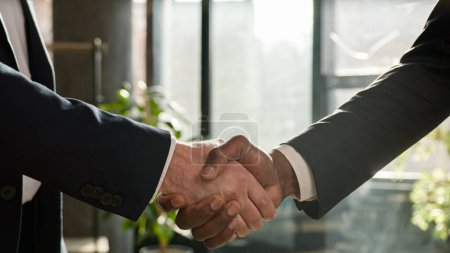 Foto de Close up two diverse men shake hands multiracial businessmen concluded successful contract agreement multiethnic business partners handshake support partnership cooperation greeting in office male arms - Imagen libre de derechos