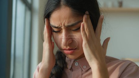 Téléchargez les photos : Fatiguée femme malade arabian fille indienne près de la fenêtre à la maison souffrent de maux de tête toucher douloureux migraine douleur malsaine femme malade penser pensées difficiles chagrin santé trouble stress fatigue covide - en image libre de droit