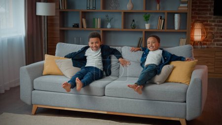 Photo for Happy family two adopted African American ethnic little boys children siblings kids resting together in living room relaxing on sofa laugh smiling relax lying on cozy couch daycare custody childhood - Royalty Free Image