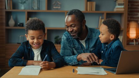 Photo for Happy smiling family e-learning home education African American father man private teacher with two boys kids children help little schoolboy son child boy with school homework teaching writing task - Royalty Free Image