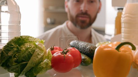 Photo for Point of view POV inside refrigerator Caucasian man husband guy male homeowner chef cooker open fridge door full of healthy fresh vegetables take out sniff tomato for cooking at kitchen food delivery - Royalty Free Image