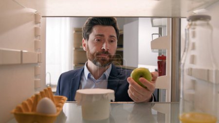 Photo for Point of view POV inside empty refrigerator Caucasian sad hungry businessman upset man open fridge with one egg empty bottle of juice searching snack take apple fruit diet need products food delivery - Royalty Free Image