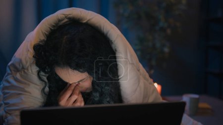Foto de Chica agotada mujer de negocios fatigada mujer cansada hispana somnolienta mujer árabe india sobrecargada de trabajo por la noche casa de noche bajo la manta edredón cubierta con computadora portátil adicto bostezo dolor de cabeza fatiga visual - Imagen libre de derechos