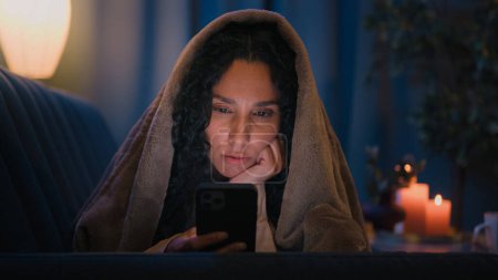 Téléchargez les photos : Téléphone portable addiction smartphone toxicomane Arabe femme Hispanique somnolent fatigué fille souffrant d'insomnie trouble du sommeil médias sociaux accro à l'aide de la technologie app internet la nuit à la maison sous couverture - en image libre de droit
