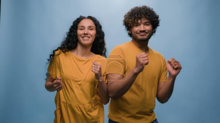 Foto de Multiracial diversa pareja india árabe hombre chico hispano caucásico mujer chica bailando juntos a la música divertirse disfrutando divertido activo movimiento danza engañando alrededor entretenimiento en azul fondo - Imagen libre de derechos